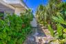Exterior side yard featuring a series of circular stone pavers and mature tropical landscaping including palm trees