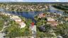 Aerial perspective of a waterfront residential property featuring an enclosed lanai and established landscaping