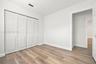 Neutral-toned room featuring wood-finish flooring, white walls, and a four-panel bi-fold closet with louvered doors