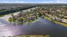 Aerial perspective of a waterfront property featuring a tile roof, paved driveway, and expansive rear water frontage