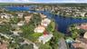 Aerial perspective of a residential property featuring a screen-enclosed pool, mature palm trees, and proximity to a community lake