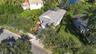 Single-story residence featuring a shingle roof, concrete driveway, attached garage, screen-enclosed pool structure, and perimeter landscaping