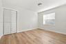 Interior room featuring wood-finish flooring, neutral wall paint, a double-panel louvered closet door, a single-window configuration with horizontal b