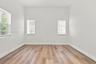 Interior room featuring wood-finish flooring, white walls, and three windows equipped with horizontal blinds