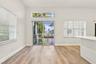 Interior space featuring wood-finish flooring, white walls, horizontal window blinds, sliding glass patio door with a transom window, and a built-in w