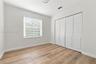 Interior room featuring wood-finish flooring, a single-panel window with horizontal blinds, and a built-in four-panel louvered closet door