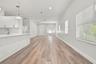 Open-concept interior featuring wood-finish flooring, white shaker-style cabinetry, a quartz-topped island, recessed lighting, and horizontal window b