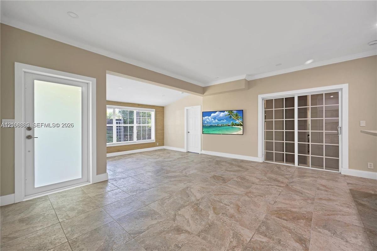 Open-concept interior featuring large-format tile flooring, multi-pane glass sliding doors, recessed ceiling lighting, and a frosted glass entry door