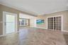 Open-concept interior featuring large-format tile flooring, multi-pane glass sliding doors, recessed ceiling lighting, and a frosted glass entry door