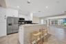 Kitchen featuring white flat-panel cabinetry, stainless steel appliances, a stone-tile breakfast bar, and tile flooring