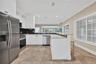 Kitchen featuring white shaker cabinetry, stainless steel appliances, a black tiled backsplash, a stone-finish countertop peninsula, and ceramic tile 
