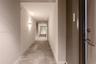 Lobby area featuring polished large-format stone-finish tile flooring, glass entry doors, recessed ceiling lighting, and a dark wood-trim architectura