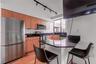 Kitchen featuring wood cabinetry, stainless steel appliances, dark stone-finish countertops, a breakfast bar, and track lighting