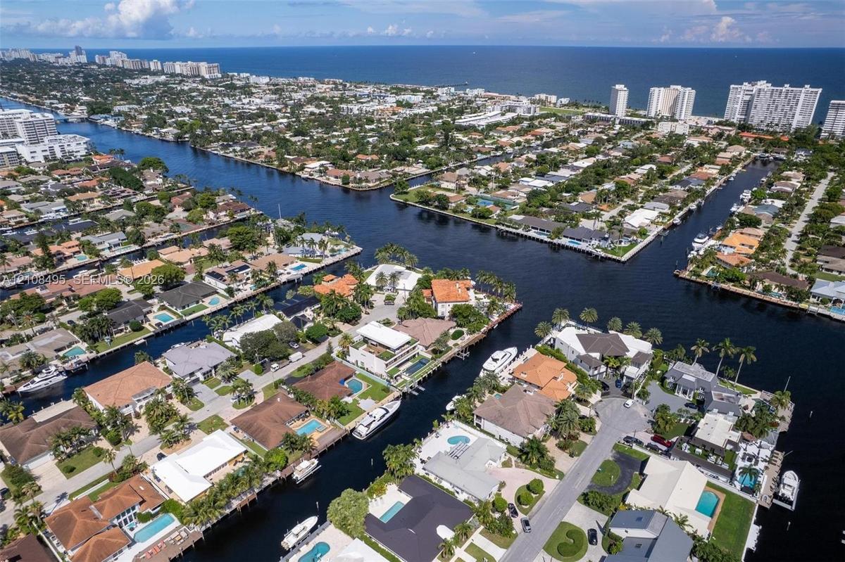 Waterfront property featuring a private boat dock, concrete seawall, in-ground swimming pool, and manicured lawn