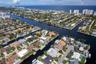 Waterfront property featuring a private boat dock, concrete seawall, in-ground swimming pool, and manicured lawn