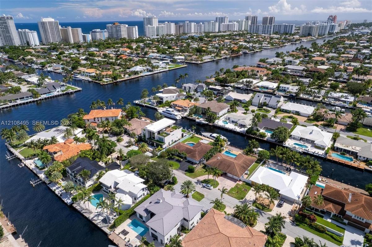 Waterfront property featuring a private boat dock, swimming pool, manicured lawn, and hardscaped patio area