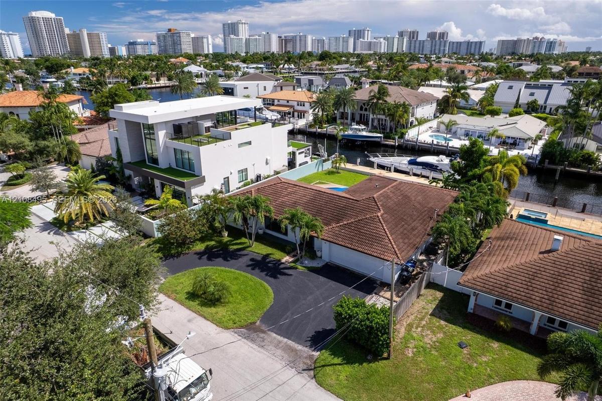 Waterfront property featuring a private concrete dock, an in-ground swimming pool, a sodded lawn, and a paved patio area