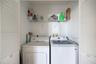 Laundry closet featuring white louvered doors and an elevated wire shelving unit