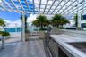 Expansive terrace featuring wood-finish tile flooring and a minimalist glass railing overlooking the water and city skyline