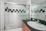 Bathroom featuring a tub-shower combination with glass sliding doors and a decorative black-and-white checkered tile accent, paired with a vanity cont