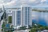 Aerial perspective featuring a glass-facade high-rise tower, expansive coastal waterfront, and urban skyline