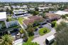 Aerial view of a waterfront property featuring a private boat dock, a swimming pool, a tiled roof, and a paved driveway