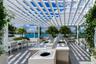 Outdoor terrace featuring a white pergola, stainless steel built-in grill, stone-surface countertop, and large planters