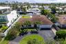 Aerial perspective of a waterfront property featuring a canal-front bulkhead, private swimming pool, concrete patio, paved driveway, and tile roof