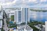 High-rise residential tower featuring white structural facade, tiered balcony design, onsite tennis court, and immediate waterfront positioning