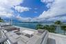Expansive private terrace featuring large-format porcelain tile flooring and a frameless glass balustrade overlooking the water and metropolitan skyli