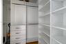 Custom walk-in closet featuring white laminate cabinetry, four soft-close drawers with metallic pulls, adjustable shelving, and dual-level metal hangi