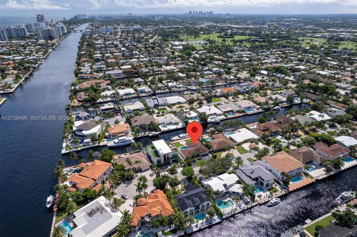 Waterfront property featuring a tile roof, paved driveway, swimming pool, and private boat dock
