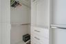 Built-in closet system featuring white cabinetry, integrated shelving, tiered hanging rods, and a stack of three drawers with metallic hardware