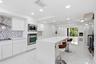 White shaker cabinetry, stainless steel appliances, herringbone tile backsplash, recessed lighting, and a kitchen island with a white countertop