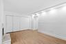 Recessed lighting, wood-finish flooring, white walls, built-in closet with sliding doors, and a fireplace with a stone surround