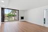 Wood-finish flooring throughout, recessed ceiling lighting, a built-in fireplace with a stone surround, and an expansive sliding glass door to the ext