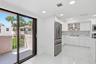 Modern kitchen featuring white cabinetry, stainless steel appliances, and a herringbone tile backsplash, dining area