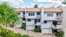 Multi-level exterior with tile roofing, private balconies, integrated garages, and mature landscaping