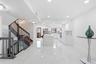 Sophisticated open-concept living space featuring polished light-finish flooring throughout, a curved staircase with metal railings and wood treads, r