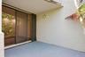 Sliding glass doors with screen, textured exterior wall, exterior wall light fixture, and concrete patio