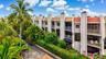Multi-level townhome featuring white stucco exterior, terracotta roof tiles, and multiple balconies with white railings
