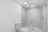 Walk-in shower with clear glass enclosure, tiled walls, and a rainfall showerhead