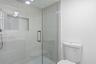 Glass-enclosed shower with a recessed niche, rain shower head, and an attached handheld shower fixture