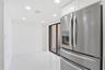 Stainless steel French door refrigerator, white cabinetry, recessed lighting, white flooring, and sliding glass door