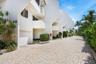 White stucco exterior with multiple balconies, private garages, and a paver driveway