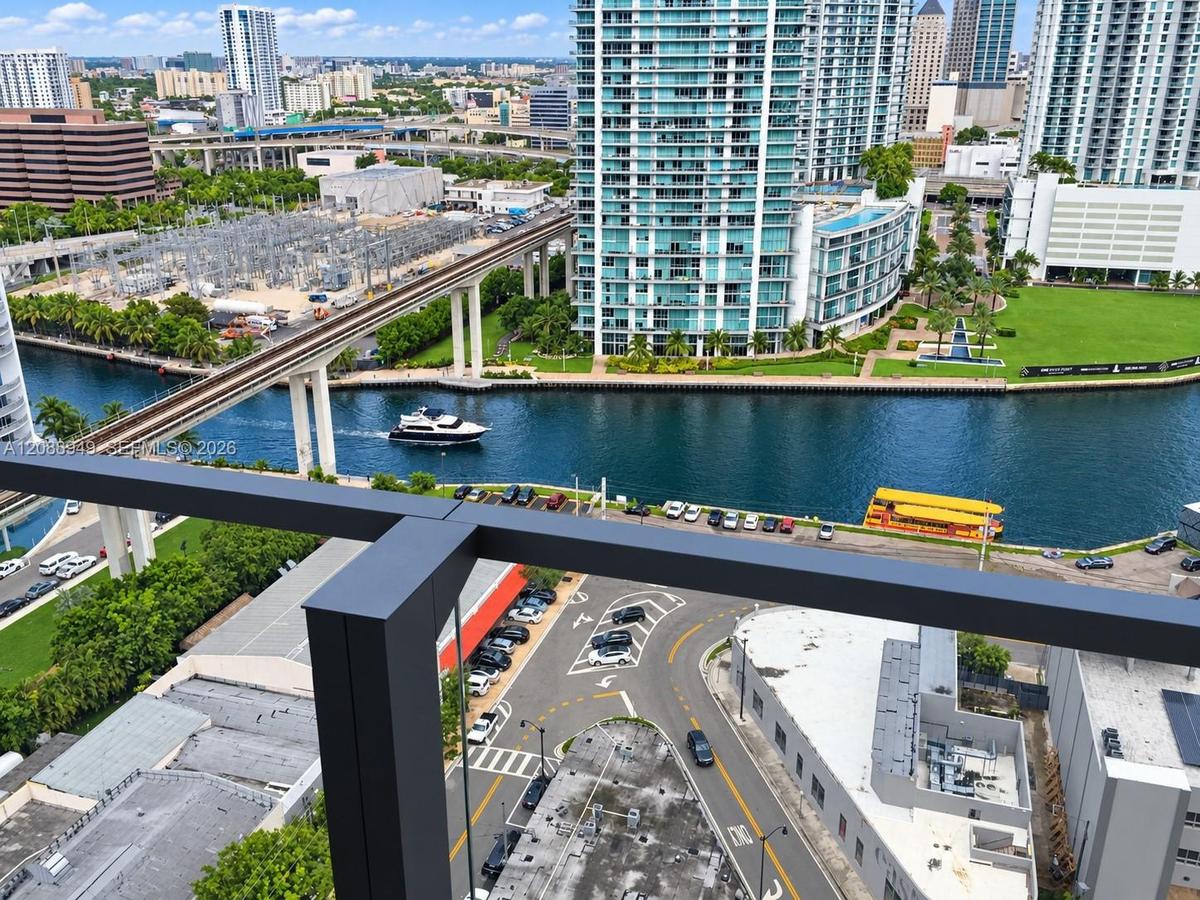 Elevated balcony featuring a dark metal railing, offering direct exposure to the urban skyline, waterway, and transit infrastructure