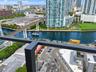Elevated balcony featuring a dark metal railing, offering direct exposure to the urban skyline, waterway, and transit infrastructure