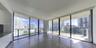 Floor-to-ceiling glass walls, expansive wraparound balcony with glass railing, and large-format tile flooring