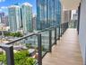 Expansive private balcony featuring wood-finish tile flooring and a sleek frameless glass railing system with dark metal supports