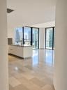 Polished stone flooring, floor-to-ceiling windows, white cabinetry, integrated kitchen island with stone countertop, and recessed ceiling lighting